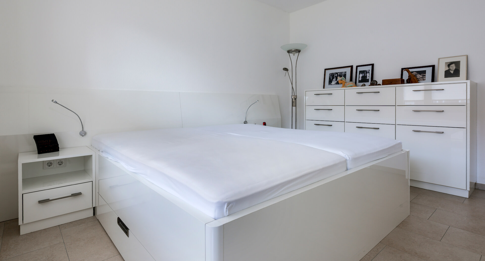 In weiß gehaltenes Schlafzimmer mit Bett und Möbeln